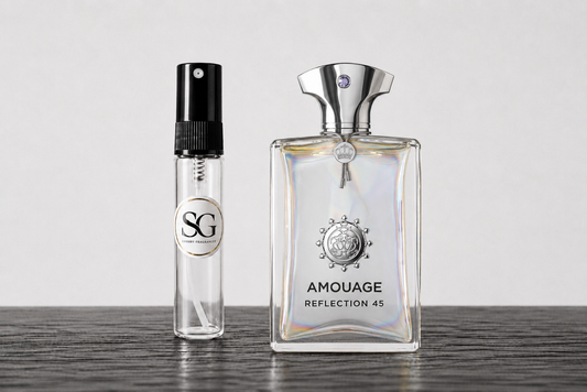 Amouage Reflection 45 perfume bottle next to a small clear glass sample spray vial with a black atomizer and a circular SG label, set on a dark wooden surface against a light gray background.