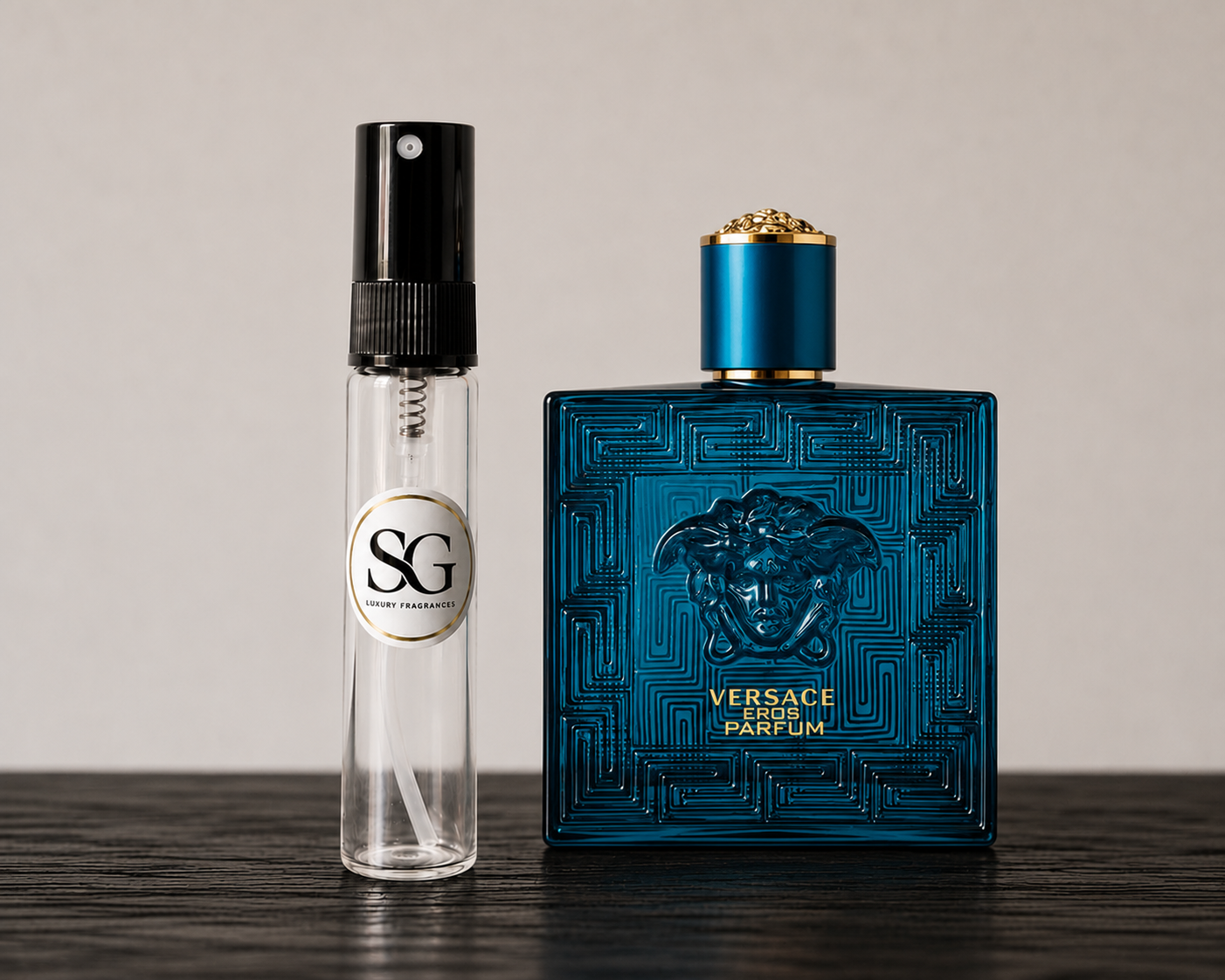 Blue Versace perfume bottle and a smaller clear bottle with black cap on a wooden surface.