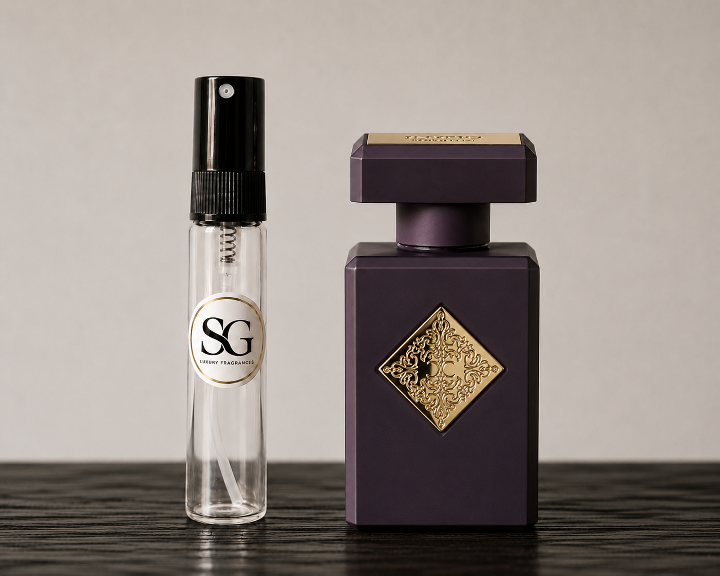 Two perfume bottles, one clear with black cap and gold label, the other dark purple with gold design, on a wooden surface.