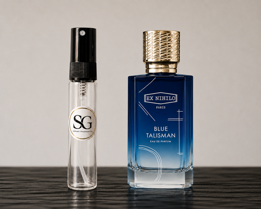 Two perfume bottles, one clear with black cap and gold logo, the other blue with gold cap, on a wooden surface.