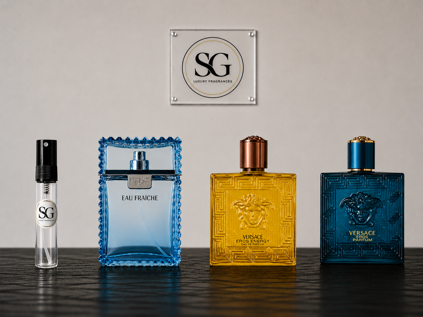 Four Versace perfume bottles on a reflective surface with a branded plaque in the background.